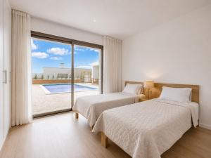 two beds in a bedroom with a view of a pool at Villa Flamingo - BY SCH in Nadadouro +15 photos