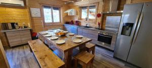 a kitchen with a wooden table and a refrigerator at Chalet Enchanteur à Venosc avec Vue Panoramique et Jacuzzi in Vénosc