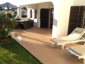 a patio with two lounge chairs and an umbrella at Charming House in Carvoeiro + Pool in Carvoeiro