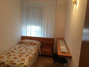 a bedroom with a bed and a desk and a window at Spacious Apartment in Terrassa with Shared Pool, 85 m² in Terrassa