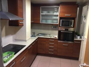 a kitchen with wooden cabinets and a stove top oven at Spacious Apartment in Terrassa with Shared Pool, 85 m² in Terrassa