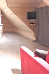 a living room with a red couch and a tv at Studio cosy à Saint-Jean-d'Arves 29 m² Vue montagne in Saint-Jean-dʼArves +20 photos