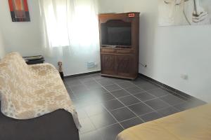 a room with a bed and a tv and a couch at Bright apartment in Almada with shared pool in Almada