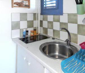 a kitchen sink with a blue chair next to it at Studio confortable à Sainte-Anne 30 m² avec vue mer in Sainte-Anne