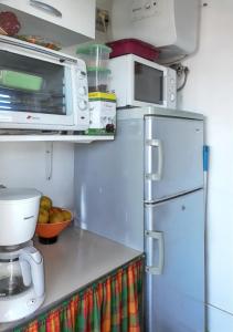 a kitchen with a microwave and a refrigerator at Studio confortable à Sainte-Anne 30 m² avec vue mer in Sainte-Anne