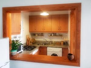 a kitchen with wooden cabinets and a sink and a dishwasher at Charming House in El Chaparral in EL Chaparral