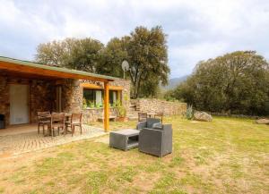 a stone house with a table and chairs in a yard at Appartement confortable à Moltifao, vue sur montagne, 50 m² in Moltifao