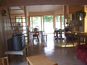 a living room with a tv and tables and chairs at Villa ensoleillée à Saint Hilaire de Riez avec piscine privée in Saint-Hilaire-de-Riez