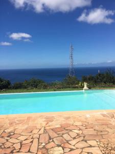 a swimming pool with the ocean in the background at Villa Enchantée avec Vue sur mer et Piscine au Carbet in Le Carbet +10 photos