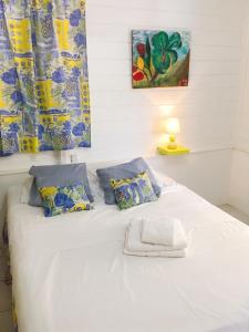 a large white bed with blue and yellow curtains at Villa Enchantée avec Vue sur mer et Piscine au Carbet in Le Carbet