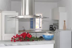 a kitchen with red flowers and a bowl on a counter at Charming House in Paros, 90 m² with Shared Pool in Parikia