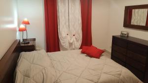 a bedroom with a bed with a red pillow on it at Villa charmante à Saint-Benoît avec piscine privée in Saint-Benoît