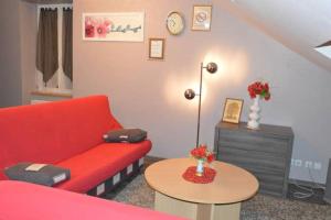 a living room with a red couch and a table at Appartement chaleureux à Gérardmer avec parking privé. in Gérardmer