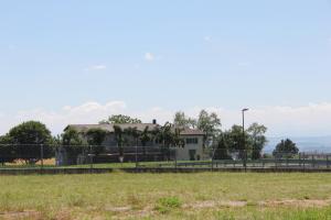 a house behind a fence in front of a field at Comfortable studio in Bevaix with mountain view - 30 m² + Spa in Bevaix