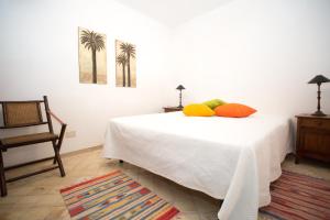 a bedroom with a white bed and a chair at Charming House in Lipari with Sea View in Lipari