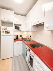 a kitchen with white cabinets and a red counter top at Apartamento de 2 dormitorios en el centro de Burgos junto a la Catedral in Burgos