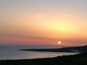 a sunset over a body of water with the sun in the sky at Charming house with sea and mountain views in El Chaparral in EL Chaparral +7 photos