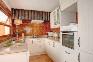 a kitchen with white cabinets and a tile wall at Modern Villa in Nazaret with Private Pool in Nazaret +22 photos