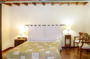 a bedroom with a bed and two tables and a chair at Luxurious Villa in Outeiro - Private Pool in Santa María La Mayor del Rosario
