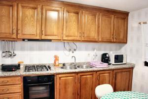a kitchen with wooden cabinets and a sink at Charming House in Paredes do Rio with Mountain View in Paredes do Rio