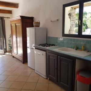 a kitchen with a white refrigerator and a sink at Maison confortable avec piscine à Saint-Julien-de-la-Nef in Saint-Julien-de-la-Nef