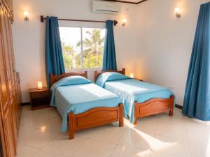 two beds in a room with blue curtains and a window at Elegant Villa with Sea View in Victoria in Victoria +7 photos