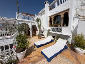 a patio with two white chairs and a building at Bright Riad with Panoramic Views - Oudayas in Rabat
