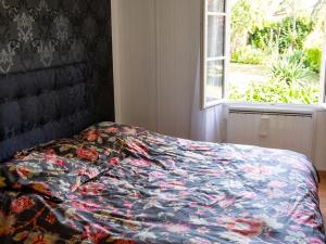 a bed with a colorful comforter next to a window at Villa de charme à Ribérac avec piscine privée in Ribérac +13 photos
