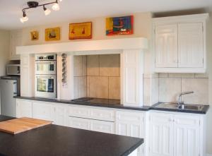 a kitchen with white cabinets and a black counter top at Spacious house with sea and mountain views, Co. Kerry in Kells
