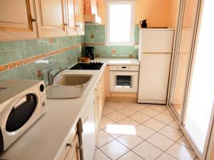 a kitchen with a sink and a white refrigerator at Villa ravissante à Loubressac avec piscine privée in Loubressac