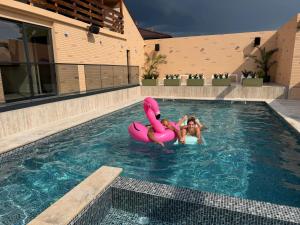 two people are in a swimming pool with a pink raft at Hanul Marioarei in Buneşti