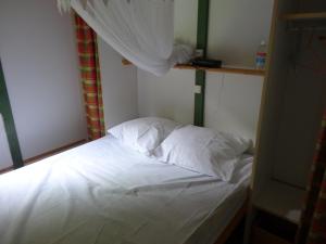 a bed with white sheets and pillows in a room at Bungalow Charmant à Pointe-Noire in Pointe-Noire