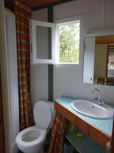 a bathroom with a toilet and a sink and a window at Bungalow Charmant à Pointe-Noire in Pointe-Noire
