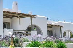 a white house with flowers in front of it at Spacious house with sea view in Ag. Arsenios, garden in Glinádhon