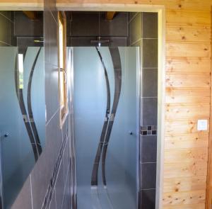 a glass shower in a bathroom with wooden walls at Chalet charmant à Saint-Gènes-Champespe avec parking privé in Saint-Genès-Champespe