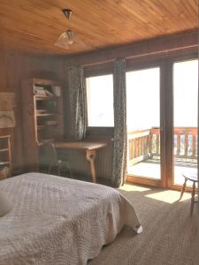 a bedroom with a bed and a desk and windows at Chalet spacieux à Cordon 180 m² avec vue montagne in Cordon +14 photos