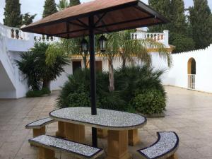 a picnic table with an umbrella and two benches at Spacious Villa in Conil de Frontera with Private Pool in Roche