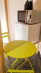 a yellow table in front of a microwave at Studio confortable à Taninges, 25 m² avec vue sur jardin in Taninges +6 photos