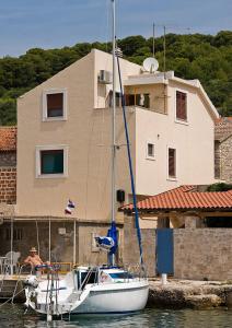 a boat is docked in front of a house at Sea View Apartment in Prvić Luka, 46m², Terrace in Prvić Luka