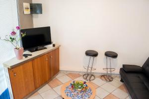 a living room with a flat screen tv and two stools at Appartement confort au Diamant 25 m² terrasse in Le Diamant