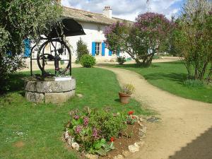 a garden with a waterwheel in front of a house at Maison de charme à Saint-Vincent-la-Châtre avec piscine partagée in Saint-Vincent-la-Châtre
