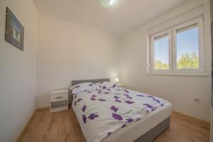 a white bedroom with a bed and a window at Bright Apartment in Vrsi with Terrace and Garden, 65 m² in Vrsi