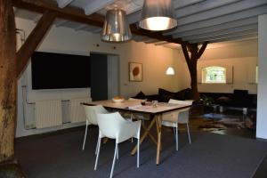 a dining room with a table and white chairs at Hof van Vijfeijken in Boxtel