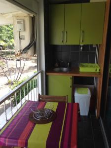 a kitchen with a table and a balcony with green cabinets at Studio charmant Le Moule 35m² + balcon in Le Moule