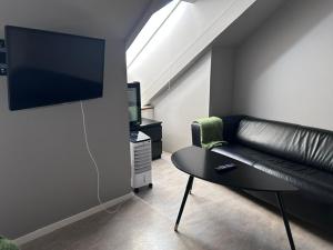 a living room with a black leather couch and a tv at Hotel Kupolen in Borlänge