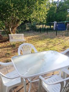a white table with two chairs and a bench at La maisonnette Poyaudine in Toucy