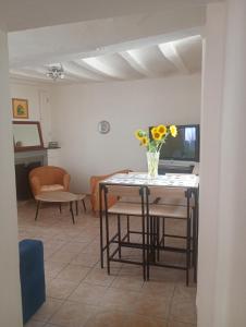 a dining room with a table with a vase of flowers on it at La maisonnette Poyaudine in Toucy