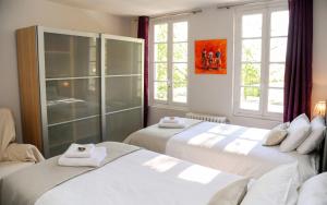 two beds in a room with two windows at Appartement contemporain à Cognac, 50 m² - Parking. in Cognac +8 photos