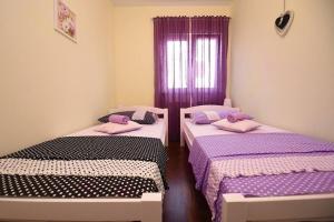 three beds in a room with purple sheets and a window at Family Villa in Solin with Pool in Solin