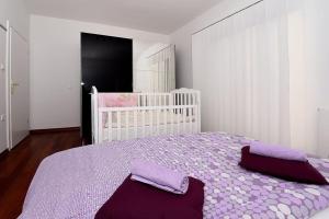 a bedroom with a bed with purple sheets and a crib at Family Villa in Solin with Pool in Solin +51 photos